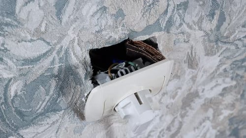 Hand plugging electrical plug into wall socket