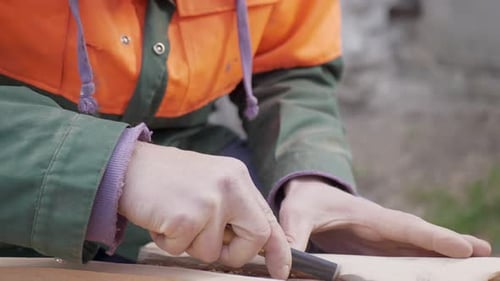 Man Carving Wood with a Chisel Outdoors