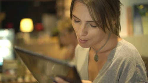 Young Woman with Tablet Computer Drinking Coffee in Cafe 30s