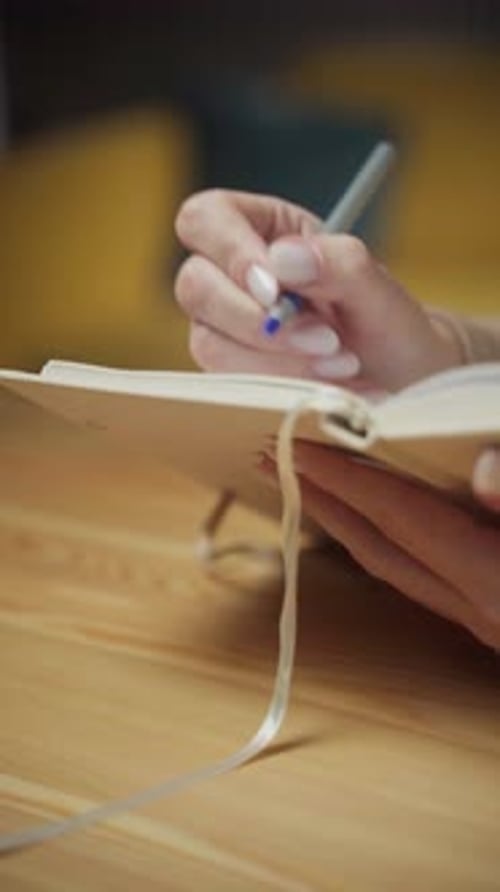 Hands Writing in a Journal with Blue Pen