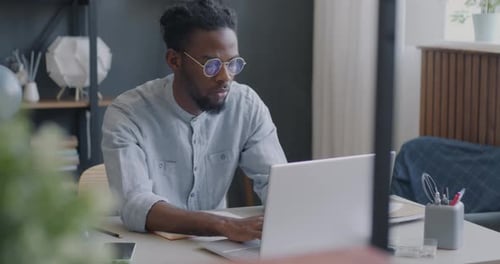 Young Adult Works on Laptop at Desk Indoors