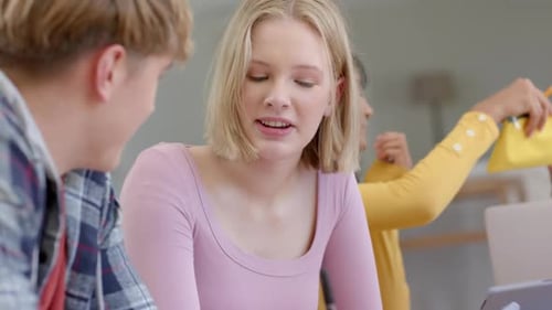 Joyeux groupe diversifié d'amis adolescents qui étudient à table avec des tablettes à la maison, au ralenti