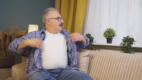 Man Fanning Shirt to Cool Off on Sofa