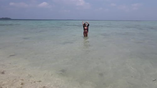 Aerial view of an Asian woman wearing bikini having a fun holiday at the beach in Karimunjawa