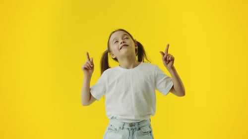 Girl Pointing Upwards on Yellow Background
