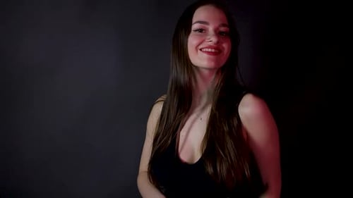 Attractive young beautiful model in black dress posing in the dark studio alone red light