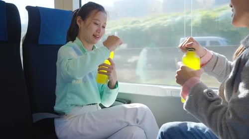 Two Friends Share Drinks on Bright Train Ride