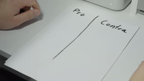 Brainstorming Pros and Cons List on Paper at Desk