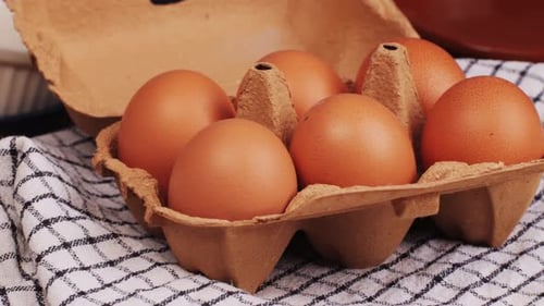 Nahaufnahme von frischen Hühnereiern und getrocknetem Stroh auf schwarzem Holztisch