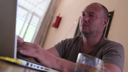 Nahaufnahme programmiert ein Softwareingenieur zu Hause auf seinem Laptop, während er in seinem Büro am Schreibtisch sitzt