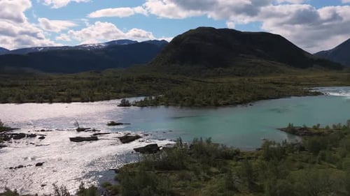 Aerial view showcasing a serene river flowing through a picturesque mountain landscape with clear bl