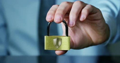 A businessman in shirt and tie shows a padlock with keys as a sign of security.The padlock symbol