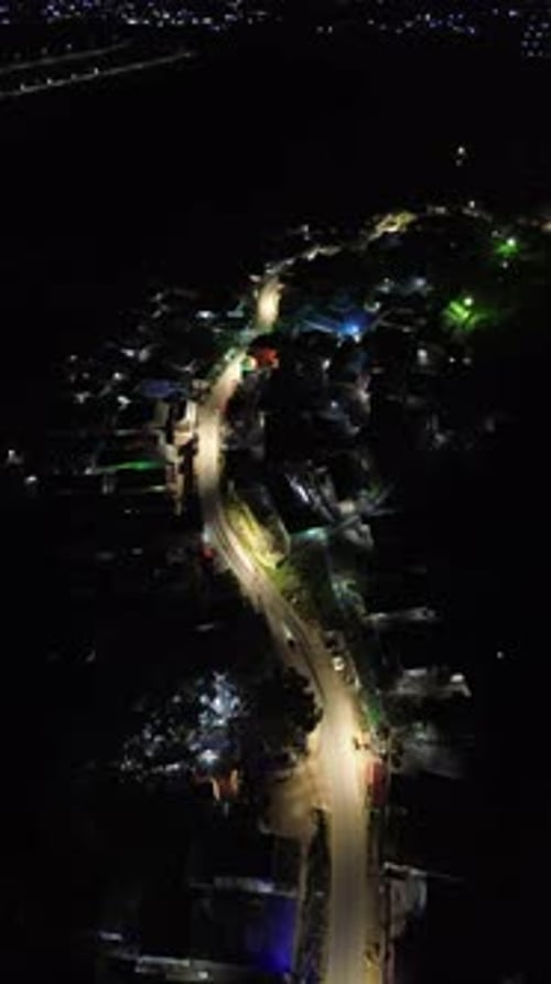 Vertical drone footage of the vehicles driving on illuminated highway roads in the city at night