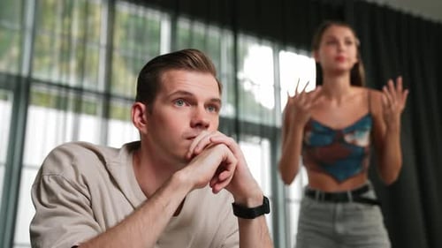 Frustrated Man Listening to Arguing Woman Indoors