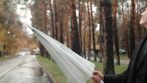 Closeup of Umbrella Opening By a Young Man in a Coat Walking on the Alley in an Autumn City Park