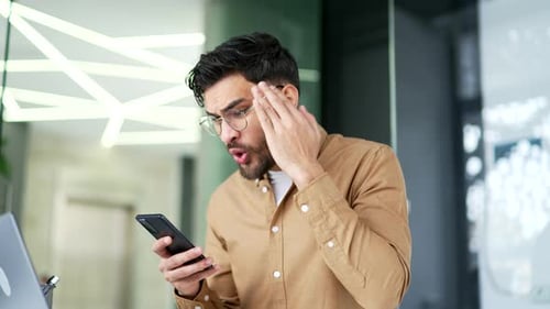 Man Reacts to Cell Phone News in Office