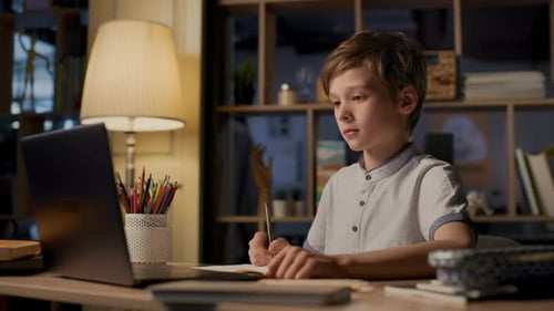 Smart school boy studies online at home during covid-19 quarantine evening