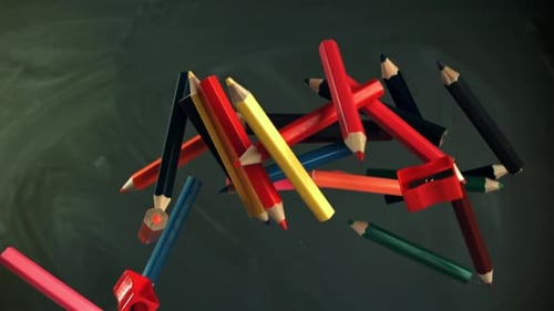 Multicolored Pencils Flying Against the Background of a Blackboard Filmed on a Highspeed Camera at
