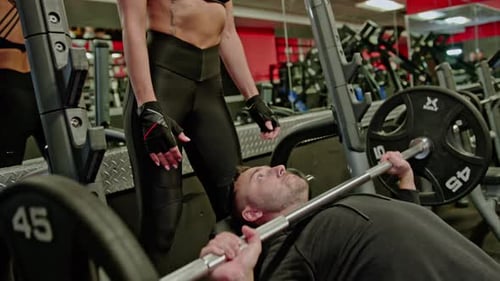 Man Doing Bench Press with Spotter in Gym