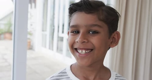 Portrait of happy biracial boy at home, slow motion