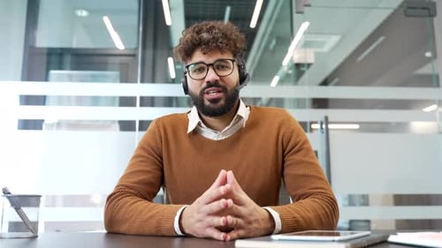 Webcam view. Confident businessman in a headset talking on a video call looking in camera sitting