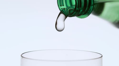 Water Pouring from Green Bottle into Drinking Glass
