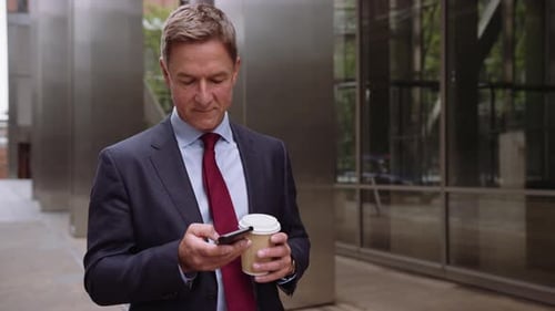 Businessman Using Phone and Holding Coffee Outdoors