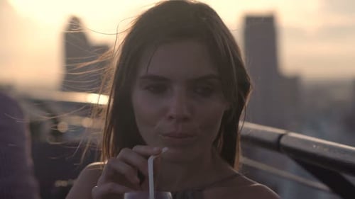 Woman Sipping Drink on Rooftop at Sunset