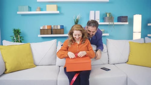 Man Surprises Woman with Birthday Gift on Couch