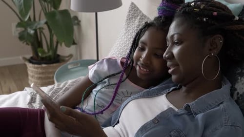 Woman and girl looking at phone on couch