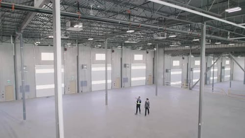 Men Walking Through Empty Warehouse in Hard Hat