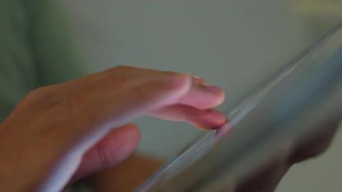 Close up young Asia male with casual cloth sit on sofa finger scroll tablet.