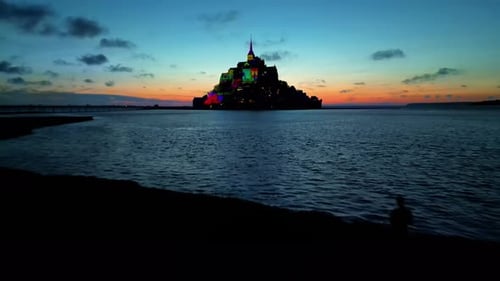 Aerial drone view of Mont-Saint-Michel at sunset in Normandy, France. Illumination in the town, wate