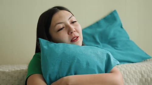 Woman Comforting Herself With a Pillow on Couch