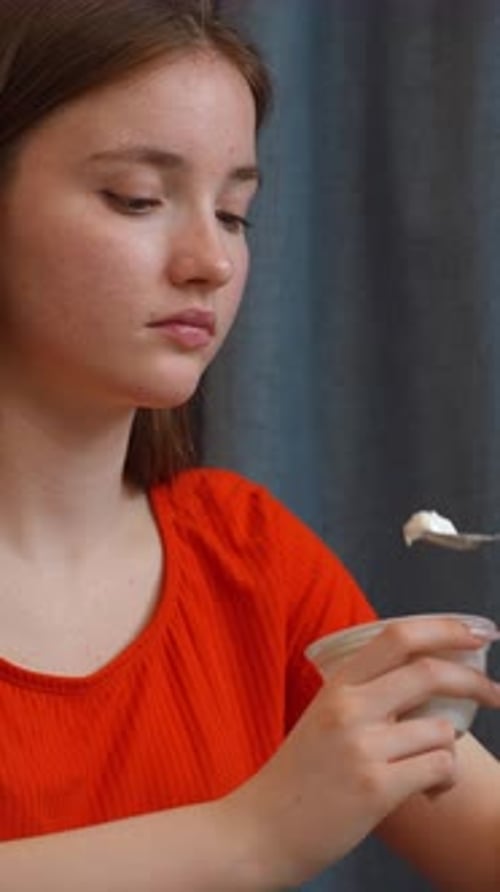 Young Woman Eating Yogurt with Spoon