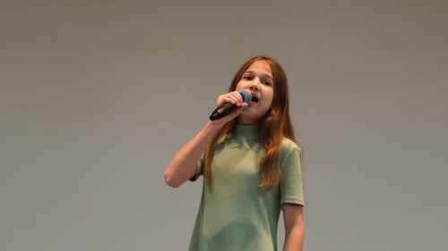 Young Girl Singing Into Microphone During Performance