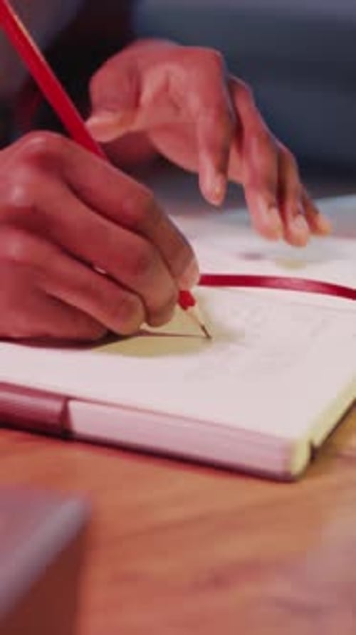 Hand Writes in Notebook With Red Pencil