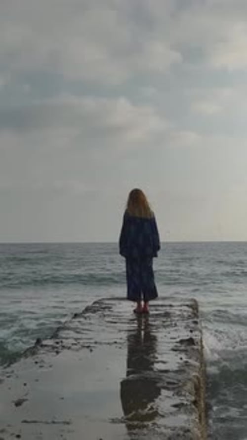Vertical Video Elegant Model Strolling Along a Pier With the Mediterranean Sea Beneath Her