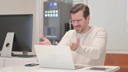 Young Man Shocked by Loss on Laptop in Office
