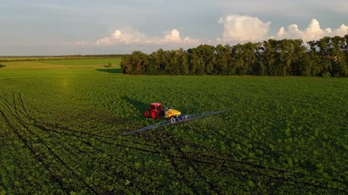 Tractor Spraying Green Agricultural Field At Sunset Aerial