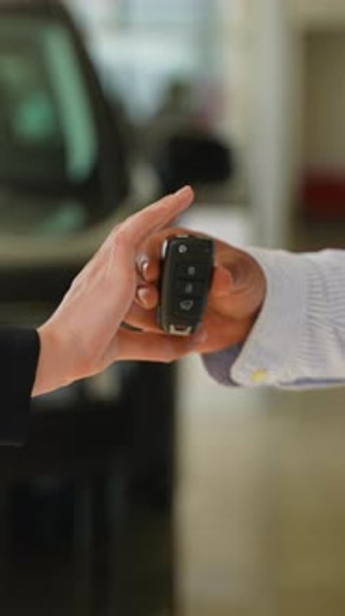 Vendedor de automóviles entrega las llaves al nuevo propietario después de un apretón de manos