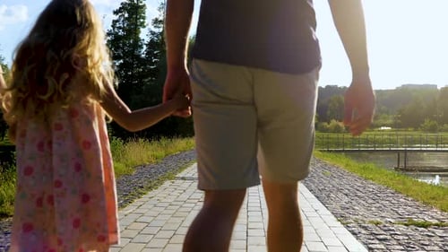 Back View of Happy Family Walking Near Beautiful Lake on Summer Day