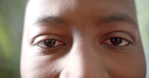 Portrait close up of eyes of happy african american man smiling in sun, slow motion
