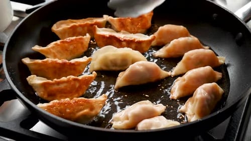 Crispy Dumplings Cooking in Pan on Stove