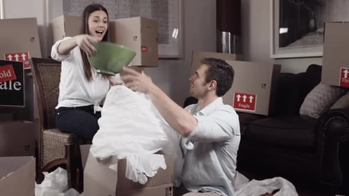 Couple Packing Dishes in Moving Boxes Indoors