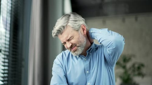 Man Massaging Neck Experiencing Painful Discomfort
