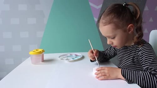 Girl Painting Figurine at Table