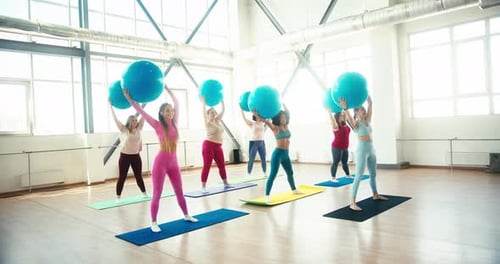 Frauen machen Fitnessübungen mit Fitball in Light Gym