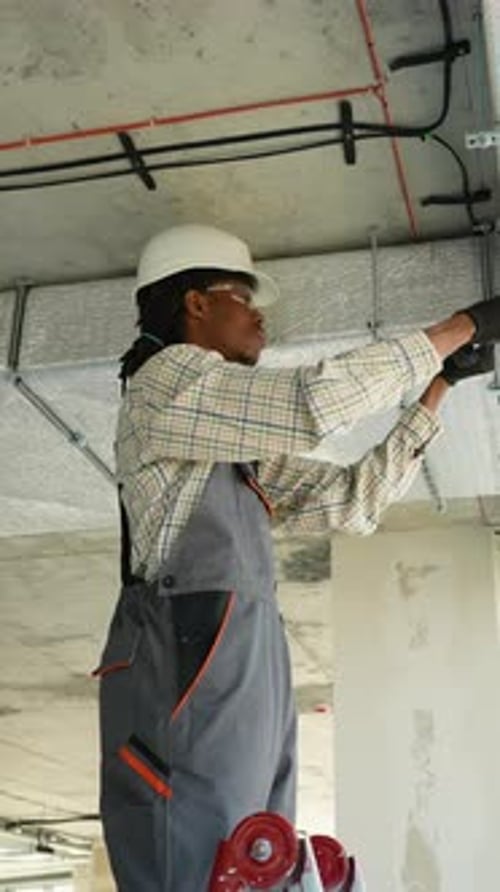 Construction Worker Installs Wiring Wearing Hard Hat