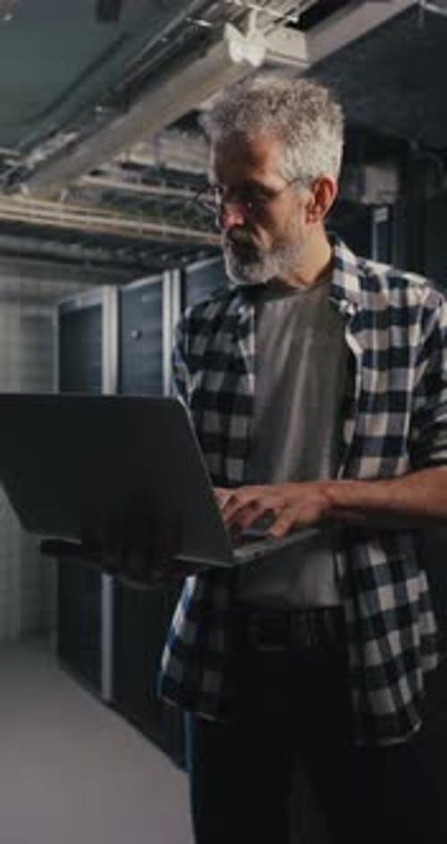 Man Working on Laptop in Front of Server